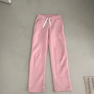 Rosa mjukisbyxor med snörning XXS - Midja rakt över: 35cm Innerbenslängd:74.     3Säljer ett par ljusrosa mjukisbyxor från russemerch i storlek XXS. Byxorna har raka ben, resår i midjan och vit snörning framtill. Mjukt och skönt material, säljer då jag ska köpa likadana i en större storlek💕