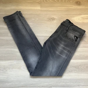Replay Anbass grå jeans slim fit - Snygga Replay Anbass jeans i tvättad grå färg med slim fit-passning. Klassisk femficksmodell med svarta detaljer och diskret Replay-logga på linningen. Jeansen har raka ben och är tillverkade i mjukt stretchigt denim för skön komfort.