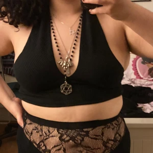 Svart ribbad halterneck topp - Säljer en svart croppad halterneck topp i strl L, men sitter mer som en M. Toppen är ribbad. Toppen fästs kring halsen med en knapp. Materialet är mjukt och stretchigt. Varan är i relativt bra skick. Frakt ingår ej.