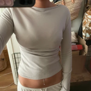 Ljusgrå långärmad topp - Säljer en stilren ljusgrå långärmad topp med tight passform och rund hals. Materialet är mjukt och tjockt, perfekt för dig som gillar minimalistisk stil. Passar dig som vill ha en enkel men snygg baströja till garderoben. 