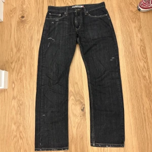 Levi's 514 straight fit - Svarta Levi's 514 jeans med straight fit och klassiska kontrastsömmar. Jeansen har slitningar och sliten detalj på bakfickan i form av ”$”, sitter skitbra