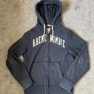 Abercrombie and Fitch hoodie - Säljer nu denna snygga hoodie då den inte passar mig! Den är i fint skick då den ska se sliten ut! Perfekt nu när de börjar bli kallare ute. Hör av dig vid eventuella frågor! :)