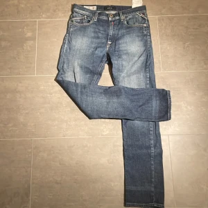  Replay jeans  - Säljer ett par klassiska blå jeans från Replay med raka ben och snygga slitningar. Jeansen har fem fickor, tydliga sömmar och läderpatch bak i midjan. Perfekta för dig som gillar en tidlös och avslappnad stil. Skriv till mig om ni har några frågor!