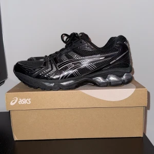 Svarta Asics Gel-Kayano 14  - Använt 1 gång och har haft de i 2 månader. Svarta Asics Gel-Kayano 14 sneakers med silvriga detaljer. Ovandel i mesh och syntet, klassisk snörning och dämpad sula med tydlig GEL-teknologi. Sportig och chunky design som passar perfekt till streetwear eller träning.