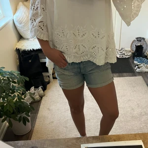 Ljusblå jeansshorts med slitningar - Säljer ett par ljusblå jeansshorts med klassisk femficksdesign och uppvikta benslut. Shortsen har låg midja och snygga slitningar framtill för en chill och trendig look. Perfekta för varma dagar och passar till allt. Materialet är mjukt denim som är skönt att bära.