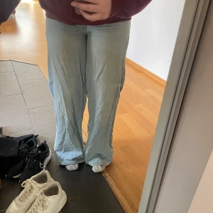 Ljusblå jeansbyxor från Bershka - Säljer ett par ljusblå jeansbyxor från Bershka med låg/ mellan låg midja. Breda bootcut. Klassisk femficksmodell med knapp och dragkedja framtill. Perfekta för en avslappnad och trendig look.