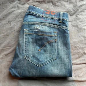 Blå Dondup Jeans - Blå jeans från Dondup med slitning som design, strl 35 i passformen George. Byxan är i mycket gott skick och är använd fåtalet gånger. Nypris ca 3500, men säljer för 999. Hör av er för fler bilder och annat!