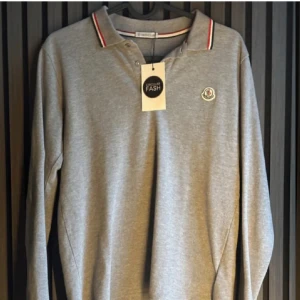 Långärmad Moncler Piké  - Moncler piké långärmad 100% äktenhetsgaranterad. Storlek 164. Sittertajt och lite kort på mig som är 178. Skulle säga att den passar bra upp till 172. Skicket är helt perfekt förutom ett minimalt hål i ena armhålan