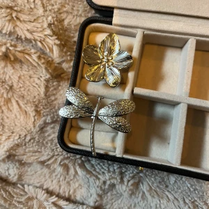 Stora silverringar med blomma och trollslända - Två unika och chunky ringar i silverfärgad metall, en med en detaljerad blomma och en med en cool trollslända. Perfekt för dig som vill sticka ut med statement-smycken och älskar naturinspirerade former. Knappt använda 