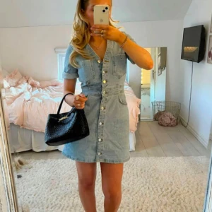 Ljusblå jeansklänning från zara - Säljer en ljusblå jeansklänning med kort ärm och snygga knappar framtill. Klänningen har v-ringning, fickor på bröstet och markerad midja. Perfekt för dig som gillar en avslappnad men trendig stil. Använt en gång