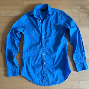 Blå skjorta från Polo Ralph Lauren - Snygg blå skjorta från Polo Ralph Lauren i slim fit med klassisk krage och vita knappar. Storlek S och är bara använd en gång. 