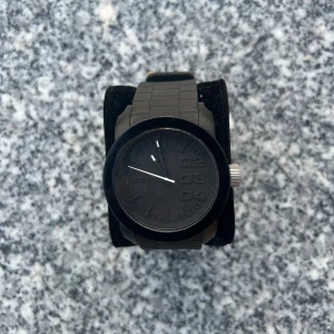 Svart klocka från Diesel med gummiband - Snygg svart klocka från Diesel med robust gummiband och stor urtavla. Klockan har en matt svart finish, tydliga siffror och detaljer i silver på kronan och spännet. Perfekt accessoar för en cool och modern stil. ⚠️OBS. Batteriet finns inte!⚠️‼️