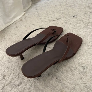 Bruna sandaler med klack och fyrkantig tå - Snygga bruna sandaler med smala remmar och fyrkantig tå. De har en låg klack och platt sula, perfekt för dig som gillar minimalistisk stil. Tillverkade i syntetmaterial. Hör av er vid intresse!