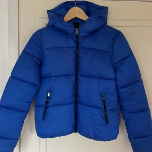Blå pufferjacka från Bershka - Blå pufferjacka från Bershka med stor luva. Jättefin, bra skick. Storlek S men skulle säga att den är lite liten i storleken.🫶🏻