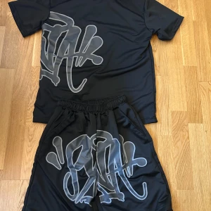 Svart Syna world set - Svart Syna World set som har en elastisk midja och är gjorda i ett lätt, syntetiskt material som känns skönt mot huden. Perfekt för dig som gillar streetwear och vill sticka ut med en cool look.           Priset kan diskuteras 
