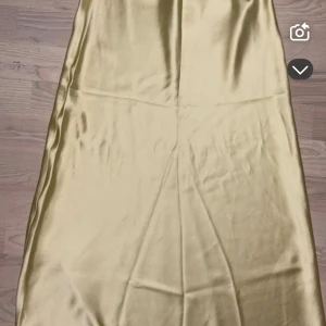 Ljusgul satinkjol från Gina Tricot - Supersnygg ljusgul långkjol från Gina Tricot i glansigt satinmaterial. Kjolen har en enkel och stilren design med lätt utsvängd form som ger en elegant siluett. Perfekt att styla med en crop top eller stickad tröja för en trendig look. Är helt oanvänd 