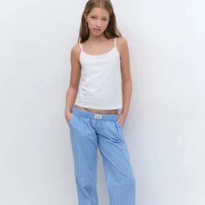 Blå randiga byxor med resårmidja - Snygga blå byxor med vita ränder och avslappnad passform. Byxorna har resår i midjan för extra komfort och raka ben. Perfekta för en chill och stilren look.