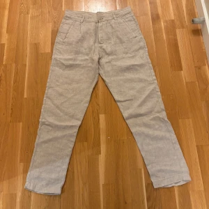 Beige linnebyxor med raka ben - Snygga beige linnebyxor med raka ben och klassisk passform. Byxorna har diskreta sidofickor, hällor för bälte och stängs med knapp och dragkedja. Perfekta för en chill och stilren look under varmare dagar.