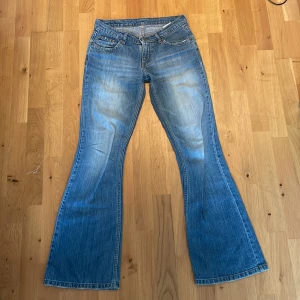 lowwaisted jeans - Snygga blå jeans från Blue Line med klassisk bootcut-passform. Jeansen har fem fickor, slitna detaljer och ljus tvätt. Tillverkade i jeansmaterial med normal midja och markerade sömmar. Perfekta för dig som gillar retrovibbar och bredare ben.
