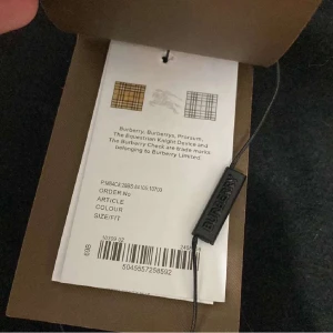 Svart Burberry hoodie med rutig huva - Svart hoodie från Burberry med dragkedja och klassiskt rutig foder i huva och insida. Hoodien har dragsko, känguruficka och är tillverkad i 100% bomull. Rutigt mönster i svart, vitt, grått och rött ger en ikonisk look. Perfekt för dig som vill ha streetstyle med lyxig touch.