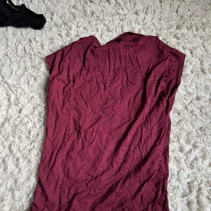 Vinröd ärmlös T-shirt  - Enkel vinröd T-shirt  i mjukt tyg med ärmlös design och rund hals. T-shirten  har rak passform och är perfekt för dig som gillar stilren och basic look. Passar till sneakers eller boots för en chill vibe.