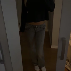 Gråa bootcut jeans med låg midja - Säljer ett par gråa jeans med låg midja och bootcut-modell. Jeansen har klassisk femficksdesign och stängs med knapp och dragkedja.