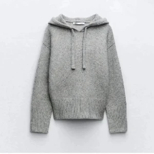Grå stickad hoodie från Zara - Mysig grå stickad hoodie från Zara med huva och snörning. Tröjan har långa ärmar och breda ribbade muddar vid ärmslut och nederkant. Perfekt för kyliga dagar och enkel att matcha med jeans eller leggings.