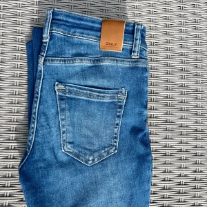 Blå bootcut jeans från ONLY - Snygga blå jeans från ONLY med klassisk femficksdesign och bootcut-ben. Jeansen har normalhög midja och är tillverkade i stretchig denim för en bekväm passform. Perfekta till sneakers eller boots och lätta att matcha med din favorit-topp.