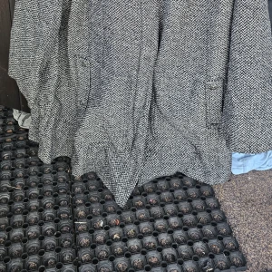 Rutig kappa från XLNT Woman - Snygg svartvit rutig kappa från XLNT Woman. Klassisk modell med knappar framtill och fickor. Tjockt, vävt material som ger en stilren och tidlös look. Perfekt för dig som gillar en trendig och sofistikerad stil.