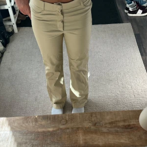 Beiga raka byxor med normal passform - Snygga beiga byxor med raka ben och klassisk femficksdesign. Byxorna har normal midja och stängs med dragkedja och knapp. Perfekta för en clean och stilren look. Materialet känns mjukt och följsamt, troligtvis bomull eller bomullsblandning.