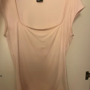 Ljusrosa ärmlös topp från Gina Tricot - Säljer en ljusrosa ärmlös topp från Gina Tricot med bred, rundad urringning. Toppen har en enkel och stilren design i mjukt bomullsmaterial, perfekt för att matcha med jeans eller kjol.