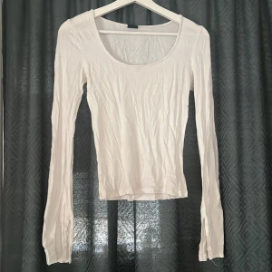 Vit långärmad topp från Gina Tricot - En basic vit långärmad topp från Gina Tricot i storlek XS. Toppen har rund halsringning, är figurnära i modellen och har utsvängda ärmar med slits.