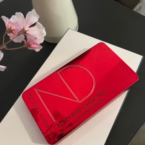 Natasha Denona Berry Pop Cheek Trio - Berry Pop Cheek Trio från Natasha Denona med en metallicröd förpackning. Paletten innehåller en mörkröd cream blush, en rosatonad glow cream base och en guldig highlighter. Perfekt för att skapa en fräsch och glowy look. Inbyggd spegel i locket.