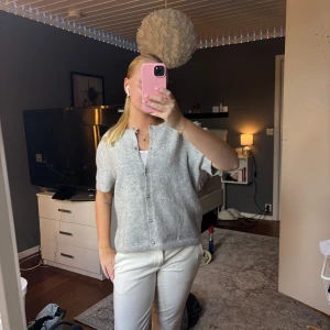 Ljusgrå kofta med kort ärm - Supermysig ljusgrå kofta med korta ärmar och pärlknappar framtill. Koftan är stickad och har en rak, lite loose passform. Perfekt att slänga över ett linne för en chill och stilren look. Jag är storlek xs/s men har medium då den är väldigt liten i storlek 