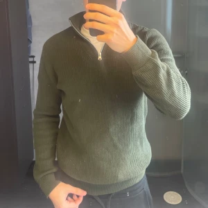 Olivgrön stickad half zip-tröja från cubus - Säljer en olivgrön stickad tröja från Cubus med half zip och hög krage. Perfekt för lager på lager! nypris 600kr