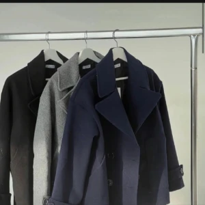 Svart skepparkavaj med stora slag - Stilren svart skepparkavaj med breda slag och dubbelknäppning. Jackan har klassisk rak passform, stora knappar och är helfodrad med glansigt innerfoder. Materialet är ullblandning som ger en snygg och tidlös look. Perfekt för dig som vill ha en clean och klassisk vibe.