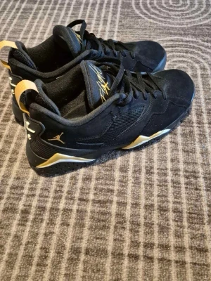 Nike Air Jordan 4 svart/guld sneakers - Snygga Nike Air Jordan 4 sneakers i svart med guldiga detaljer och klassisk Nike Air-logga på hälen. Skorna har snörning, rund tå och är tillverkade i mocka och syntetmaterial. Dom e köpta i julklapp men va för stor storlek, använda en gång hör av er om ni e intresserade💕