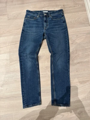  Cheap monday jeans - Säljer ett par klassiska blå jeans från Cheap Monday i regular fit. Byxorna har fem fickor, raka ben och snygga kontrastsömmar. Märkespatch i brunt läder bak i midjan och metallknappar med logga framtill. Perfekta till vardagslooken. Obs: Litet håll i ena fickan. 
