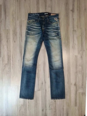 Blå Replay jeans med slitningar - Snygga blå jeans från Replay med tydliga slitningar och ljusare partier framtill och baktill. Klassisk femficksmodell med raka ben och detaljerade sömmar. Jeansen har en cool vintagekänsla och är tillverkade i denim.