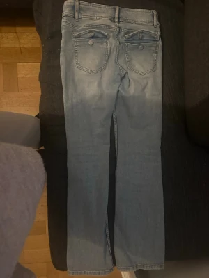 Ljusblå raka jeans från Kappahl - Säljer ett par ljusblå jeans från Kappahl med klassisk femficksdesign och raka ben. Jeansen har dragkedjegylf och knapp framtill. Perfekta för en avslappnad och trendig look.