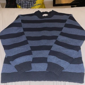 Blå och svart randig tröja Vaillent - Säljer en stickad tröja från Vaillent med breda horisontella ränder i blått och svart. Tröjan har rund halsringning och ribbstickade muddar vid ärmslut och nederkant. Perfekt för dig som gillar en avslappnad och stilren look.