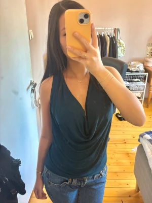 Svart draperad ärmlös topp Dagmar - Snygg svart ärmlös topp från Dagmar med draperad urringning och lös passform. Sitter verkligen perfekt. Perfekt skick. Färgen är petrol blue