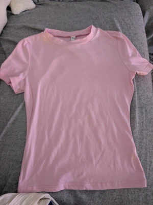 Ljusrosa t-shirt stl xs - Söt ljusrosa t-shirt  i klassisk modell med rund hals och korta ärmar. Tillverkad i mjuk bomull som känns skön mot huden. Perfekt för en enkel och stilren look.