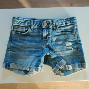Blå denimshorts med slitningar - Snygga blå jeansshorts med uppvikta benslut och slitna detaljer.