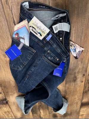 Mörkblå jeans från Jacob Cohën - Säljer ett par mörkblå jeans från Jacob Cohën med klassisk femficksmodell och snygga kontrastsömmar. Jeansen har en broderad J-logga på fickan och detaljerade innerfoder. Perfekta för dig som gillar premiumkänsla och stilren design.