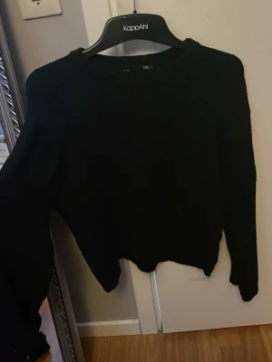 Svart stickad tröja från Lager 157 - En enkel och stilren svart stickad tröja från Lager. Tröjan har rund halsringning, långa ärmar och ribbade muddar vid ärmslut och nederkant. Perfekt basplagg till garderoben och lätt att matcha med olika outfits.