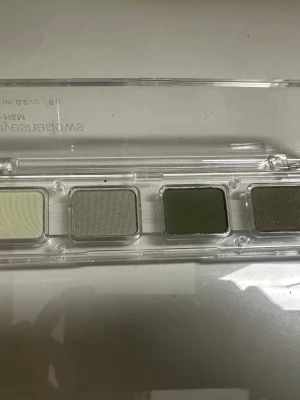 Grön ögonskuggspalett från H&M - Snygg ögonskuggspalett från H&M med fyra olika gröna nyanser, från ljus pastellgrön till mörk olivgrön och en skimrig grågrön ton. Paletten kommer i ett genomskinligt plastetui och är perfekt för att skapa olika looks med gröna toner.