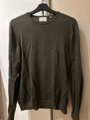 Olivgrön tröja från bläck - En stilren stickad tröja från bläck. Tröjan är i gott skick och har mycket kvar att ge!