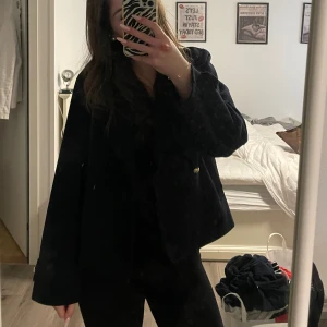 Svart kappa med guldknappar - Stilren mörk blå kappa, har fickor med lock och en klassisk, rak passform. Perfekt för en dressad look och enkel att matcha med olika outfits.