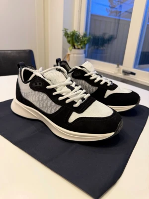  Svart Vita Dior B25 skor/sneakers - Snygga sneakers från Dior i svart och vitt med klassisk låg siluett. Ovandelen är i mesh och mocka med tydliga Dior-detaljer på plösen. Skorna har vita snören och en chunky vit sula som ger en modern look.    📦Fraktas samma dag📦  ⭐️Helt ny samt oanvänd⭐️  Har du frågor eller funderingar så hör gärna av dig🤗 ⚡️Dustbag samt box osv följs med vid köp⚡️